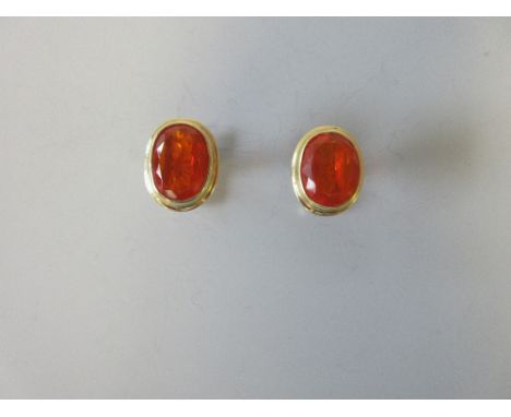 A pair of fire opal set cufflinks, each with an oval cut intense orange-red fire opal collet set to a narrow border, fixed fo