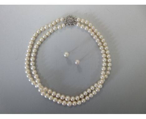 A two strand cultured pearl necklace with a diamond cluster clasp together with a pair of single pearl screwback earrings, th