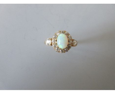 An opal and diamond cluster ring, the oval cabochon opal claw set in a border of old round brilliant cut diamonds between shi