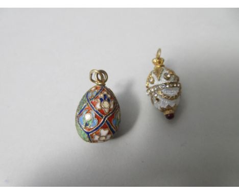 A Russian silver gilt and enamel egg pendant and another similar, the first featuring diaper panels with flowers and patterns