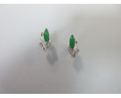 A pair of modern jade and diamond earrings, each earstud with a long marquise cabochon emerald green jade partially overlappi