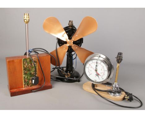 Three decorative table lamps. Includes cast iron fan, pressure gauge lamp/clock and a teak example with glass detailing.  