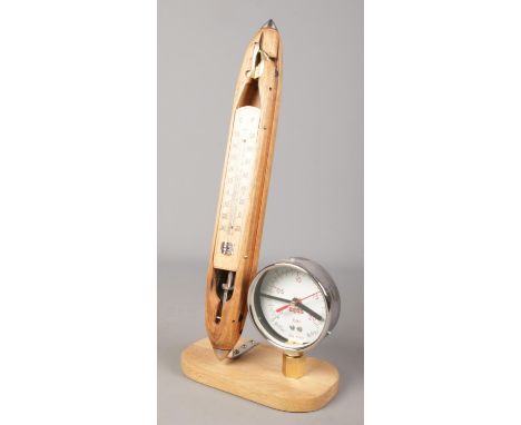 A decorative clock/thermometer formed from an antique cotton shuttle and pressure gauge.  