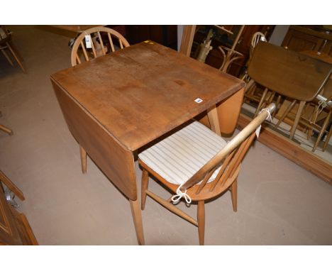 An elm Ercol drop leaf dining table, 136cms wide; and two ash Windsor style dining chairs, by B.F.H.F., dated 1960, no. 2056.