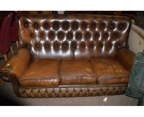 A 20th Century brown leather button back three-seater settee.