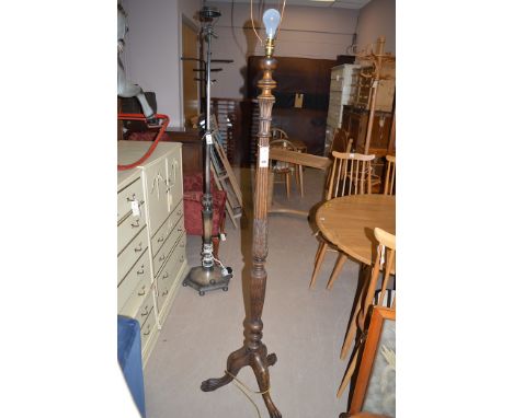 A 20th Century stained wood standard lamp, raised on tripod feet.