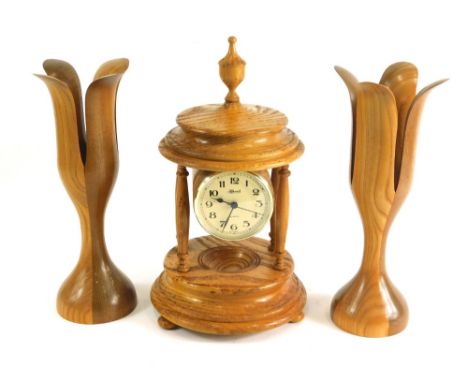 A lightwood Hermle quartz clock garniture, comprising clock with 8cm diameter Arabic dial, suspended on turned pillars, on a 