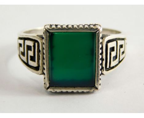 A signet ring, set with square cut jade in a rubover setting, on a white metal band with Greek key border, stamped 925, ring 