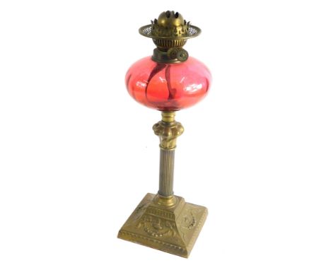A early 20thC cranberry glass and brass oil lamp, with brass fittings marked English Made, with dimpled cranberry glass reser