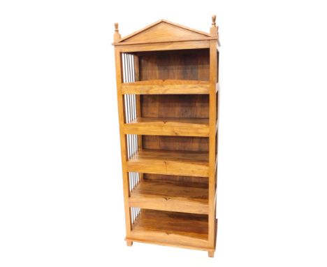 An Eastern hardwood bookcase, with a fixed architectural pediment, above open shelves with turned metal sides, on block feet,