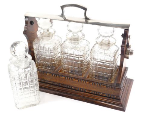A 20thC oak three bottle tantalus, with chrome plated handle and mounts, 28cm high, and a further cut glass decanter.
