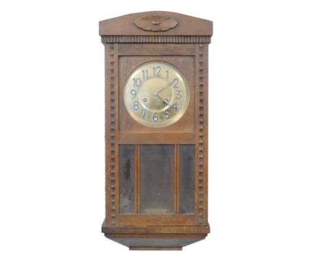 A mid 20thC oak cased wall clock, the 17cm diameter circular Arabic dial surmounted by a floral carving, in a shaped case wit