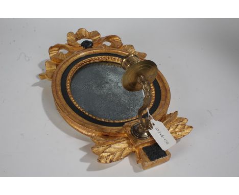 Small gilded wooden oval mirror, with ribbon tie pediment, oval glass mirror and a single branch candle sconce below, 38cm hi