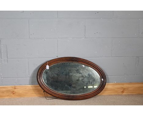 Edwardian oak framed wall mirror, the bevelled mirror plate housed in an oval bead carved frame, 79cm x 49cm