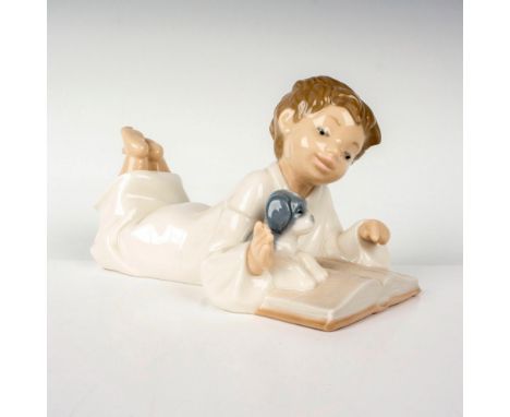 A porcelain figurine of a young boy in a white nightshirt reading a book alongside his puppy. Nao by Lladro backstamp. Dimens