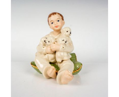 A figure depicting a young boy in white pajamas holding four puppies through his arm while sitting on the dogs' bed. Lenox ba