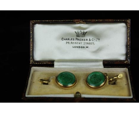 A pair of Chinese carved emerald green jade cuff links of button form, carved with Chinese characters, set in yellow metal ro