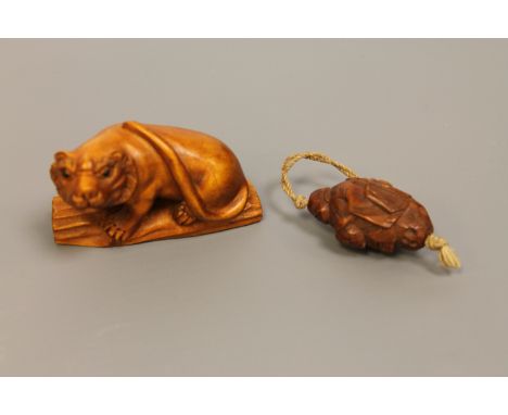 A Japanese carved wood netsuke of a tiger, together with a carved coquilla nut ojime (2)