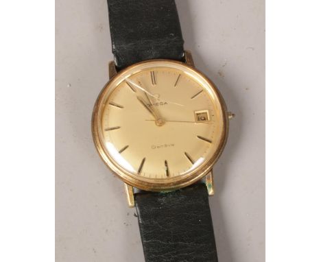 A Gentleman's Omega Geneve manual wrist watch. Gold plated, with gold satin dial, baton markers and date display.  Cracked cr