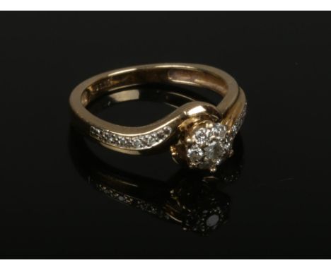 A 9ct gold diamond cluster ring set on twist shoulders. Size M.  