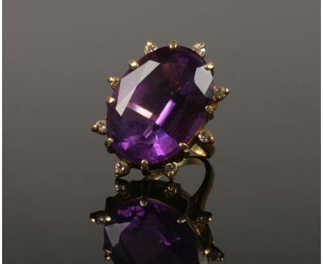 An 18ct gold amethyst and diamond cocktail ring. With a large faceted ovoid amethyst 25mm x 18mm, with eight round cut diamon