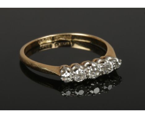 An 18ct gold and platinum ring, set with five diamonds, size M 1/2. (2.07g). Centre stone approx 0.05ct.  Good condition.