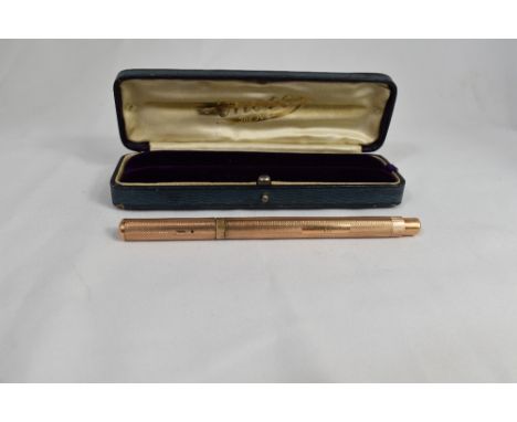 An Onoto 9ct gold pump fill fountain pen with engine turned decoration, clipless cap. Marked D L R Ltd and engraved T L Locki