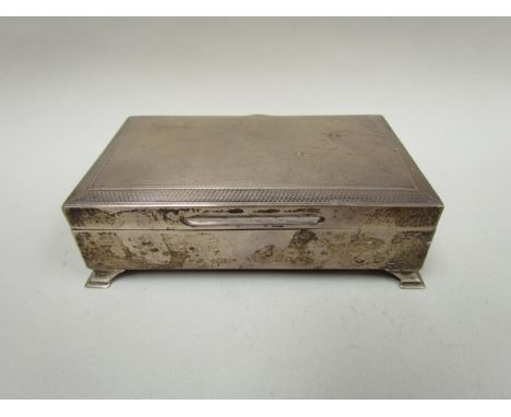 A silver cigarette case with engine turned detail, raised on four feet, Birmingham 1964, dented, wooden interior 