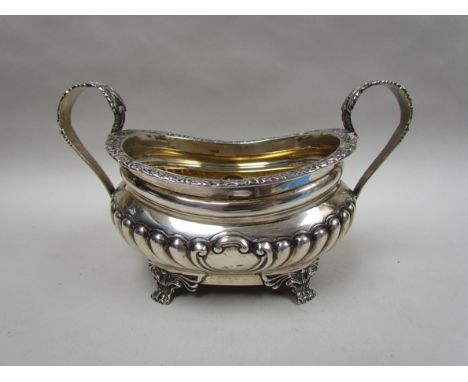 A silver twin handled sucrier, half fluted body, raised on four claw feet, London 1903, makers mark rubbed, 385g