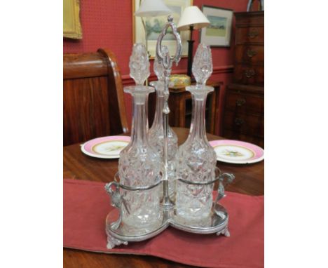 A plated three bottle decanter stand with exotic bird detail, on shell form feet