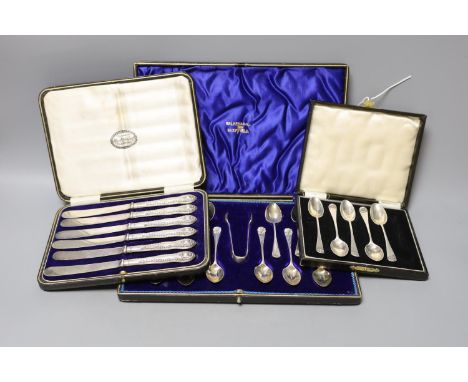 A cased set of twelve Edwardian silver teaspoons with tongs, a cased set of six tea knives and a cased set of 5 (ex 6) silver