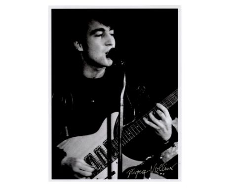 A modern black and white photograph of John Lennon performing with The Beatles at the Top Ten Club, Hamburg in 1961. It is si