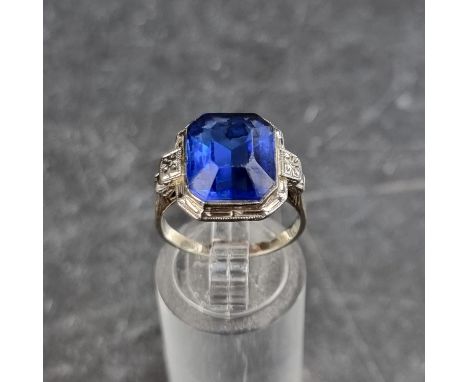 A white metal ring, set blue faceted paste, stamped '14k', size N.