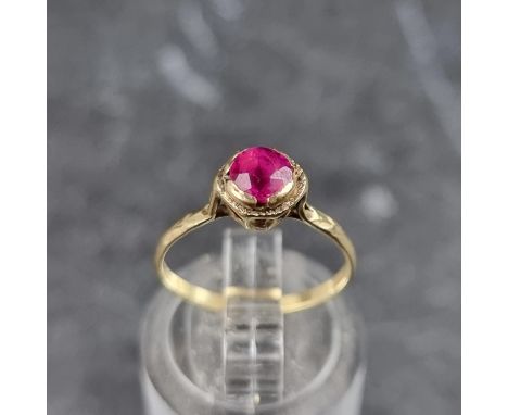 A yellow metal ring, set red gemstone, stamped 10k, size I.