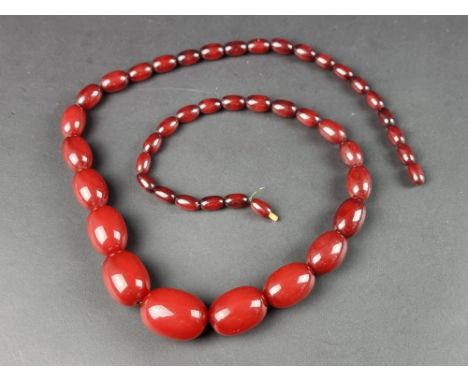 A vintage cherry amber style Bakelite necklace, having forty four beads, graduated from 33mm to 13mm, 79cm long, gross weight