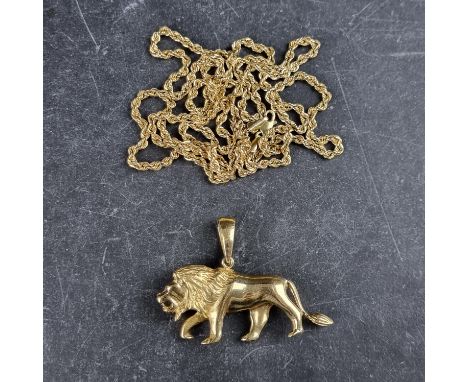 A yellow metal lion pendant, with ruby set eyes, 50mm long, with plaque stamped 18k to inside of bale, on a broken 9ct gold r