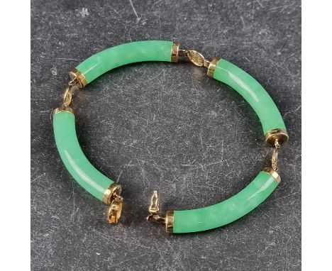 A Chinese green jade and yellow metal hinged bangle, having four curved cylindrical sections, the clasp stamped 14k 575, 18cm