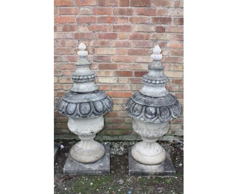 A PAIR OF LARGE STONE PEDESTAL URNS, supported on a squared foot leading to a solid swirling base, acanthus cover with moulde