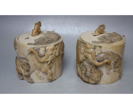 A PAIR OF 19TH CENTURY CHINESE CARVED IVORY LOW POTS AND LIDS, each with carved decoration of lions attacking an elephant, th