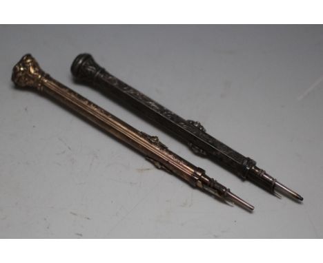 A GILT PROPELLING COMBINATION PEN AND PENCIL, with bloodstone type set finial, together with a similar white metal example (2