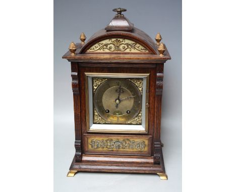 AN EARLY 20TH CENTURY OAK CASED MANTEL CLOCK BY LENZKIRCH, the architectural case with decorative gilt metal foliate panels, 
