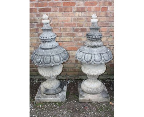 A PAIR OF LARGE STONE PEDESTAL URNS, supported on a squared foot leading to a solid swirling base, acanthus cover with moulde