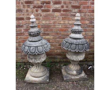 A PAIR OF LARGE STONE PEDESTAL URNS, supported on a squared foot leading to a solid swirling base, acanthus cover with moulde