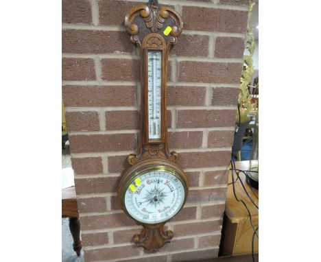 A CARVED OAK ANEROID BAROMETER
