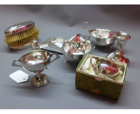 A collection of early 20th Century silver to include two gravy boat, two brushes, an ash tray, a pepperette, candlestick, con