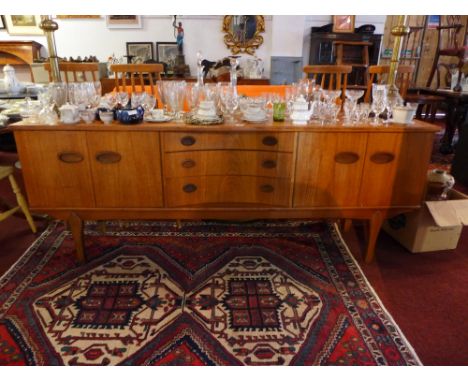 A 1970's teak sideboard with three central drawers flanked by four cupboard doors, raised on tapered legs. H-76cm, W-197cm, D