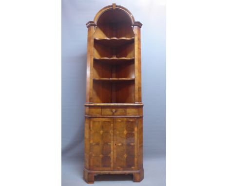 A Queen Anne style walnut corner cabinet with open shelves above single drawer, two cupboard doors and raised on carved brack