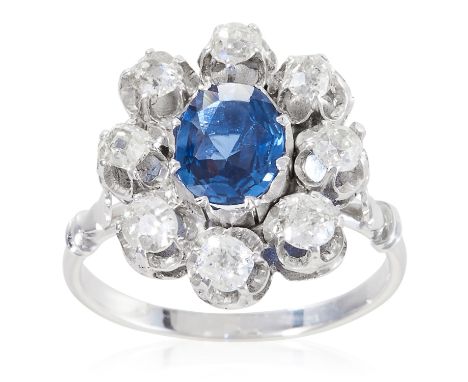 A SAPPHIRE AND DIAMOND CLUSTER RING in platinum or white gold, the oval cut sapphire encircled by old round cut diamonds tota