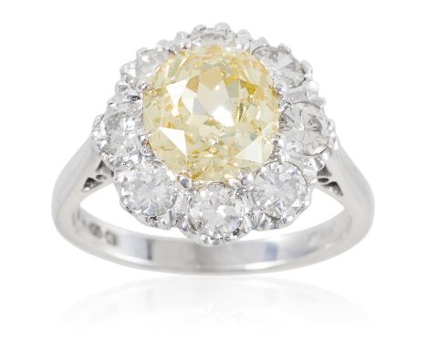 A 2.65 CARAT FANCY YELLOW DIAMOND AND WHITE DIAMOND RING in 18ct white gold, the oval cut yellow diamond of 2.65 carats, enci