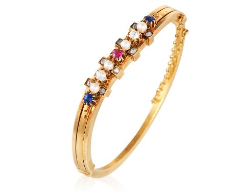 AN ANTIQUE RUBY, SAPPHIRE, PEARL AND DIAMOND BANGLE in high carat yellow gold, the undulating body set alternately with pearl